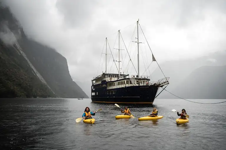 Milford Sound Overnight Cruise Boat Surrounded by Mountains and Waterfalls